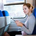 Young woman using her tablet computer while traveling by train