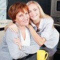 Happy adult woman with daughter on kitchen. Family at home.