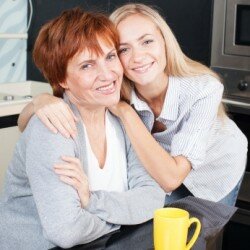 Happy adult woman with daughter on kitchen. Family at home.